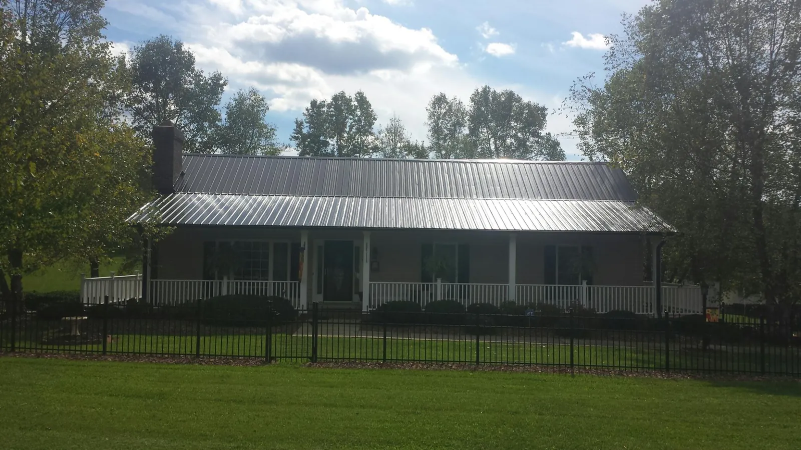 Gray metal roof on a brick ranch with a full width front porch — Gutter Guard Installation work by our crew in Pioneer